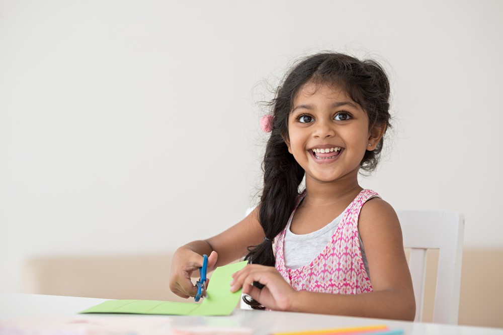 a young girl cutting a piece of paper