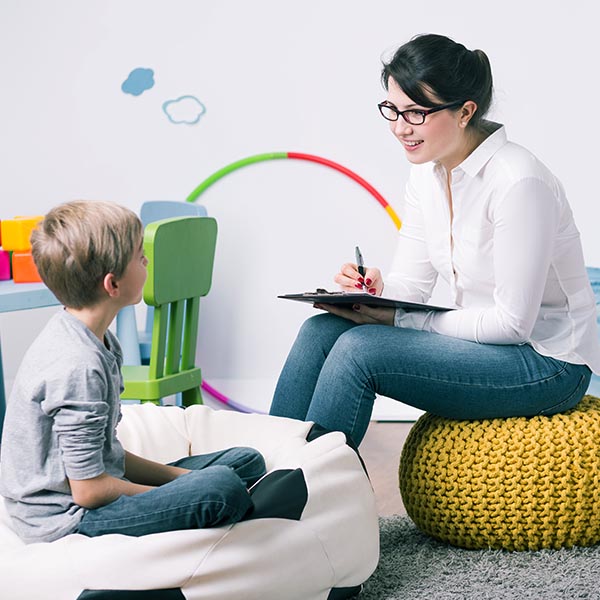 a Therapist talking to a boy on a bean bag